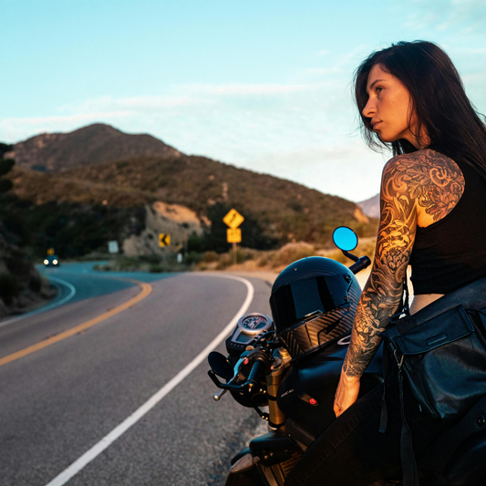 Woman sitting on her motorcycle on a winding road in California reflecting during a ride